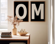 Two framed black and white letter art prints spelling out OM in a dining room.