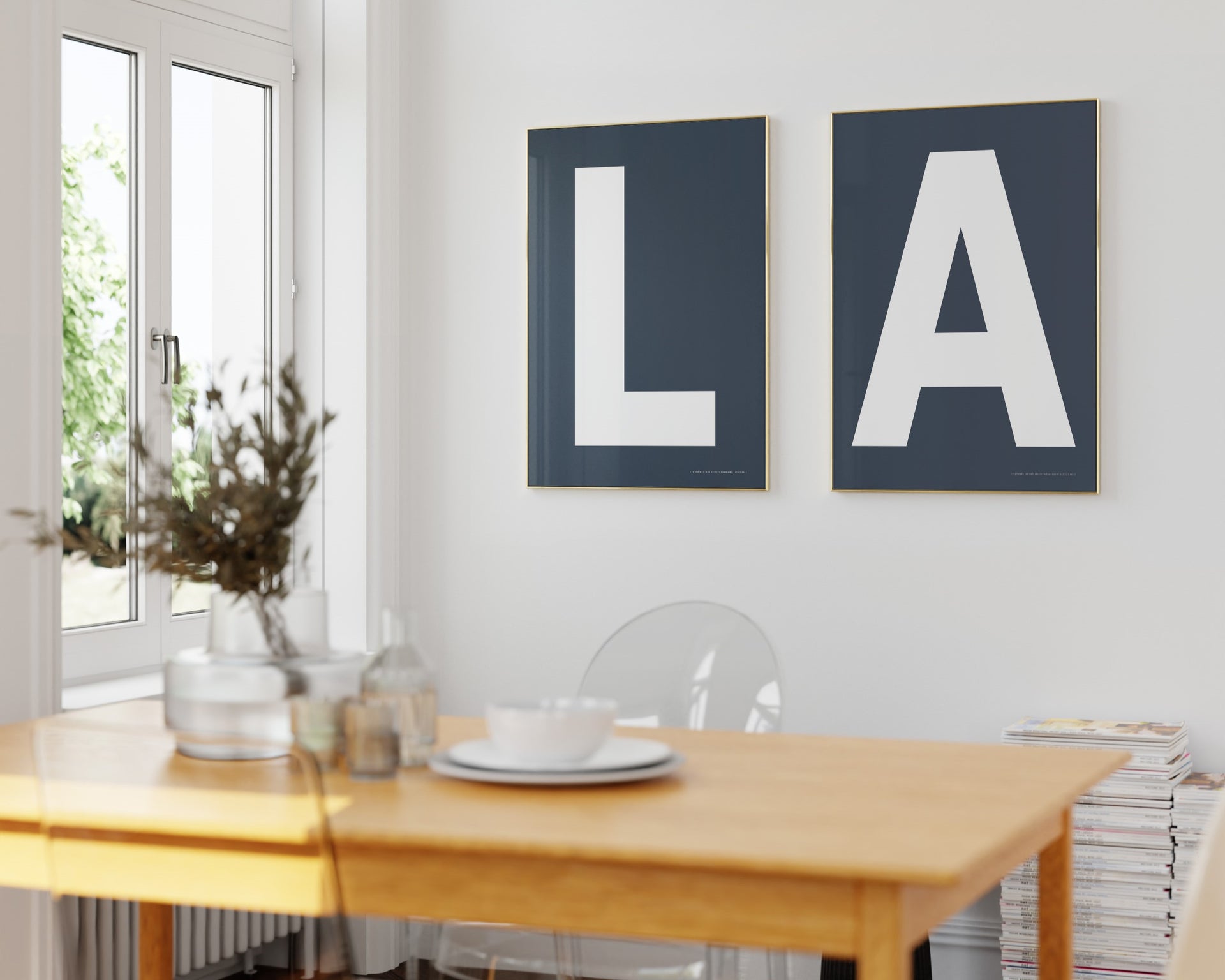 Two framed navy blue and white letter art prints spelling out LA hanging in a bright white dining room.
