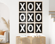Nine framed black and white letter art prints featuring X and O creating tic tac toe on the wall.