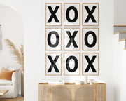 Nine framed black and white letter art prints featuring X and O creating tic tac toe on the wall.