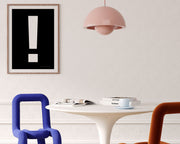 Framed black and white exclamation point hanging on a wall in a modern dining room.