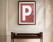 Oversized framed Nantucket red and white letter art print haning above a bence in a formal entryway or hallway.