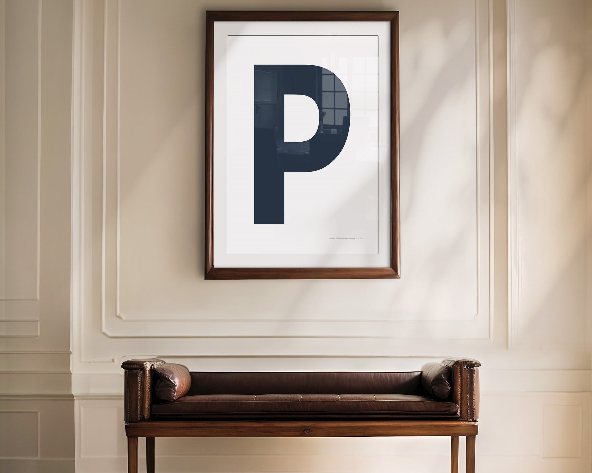 Oversized framed navy blue and white letter art print haning above a bence in a formal entryway or hallway.