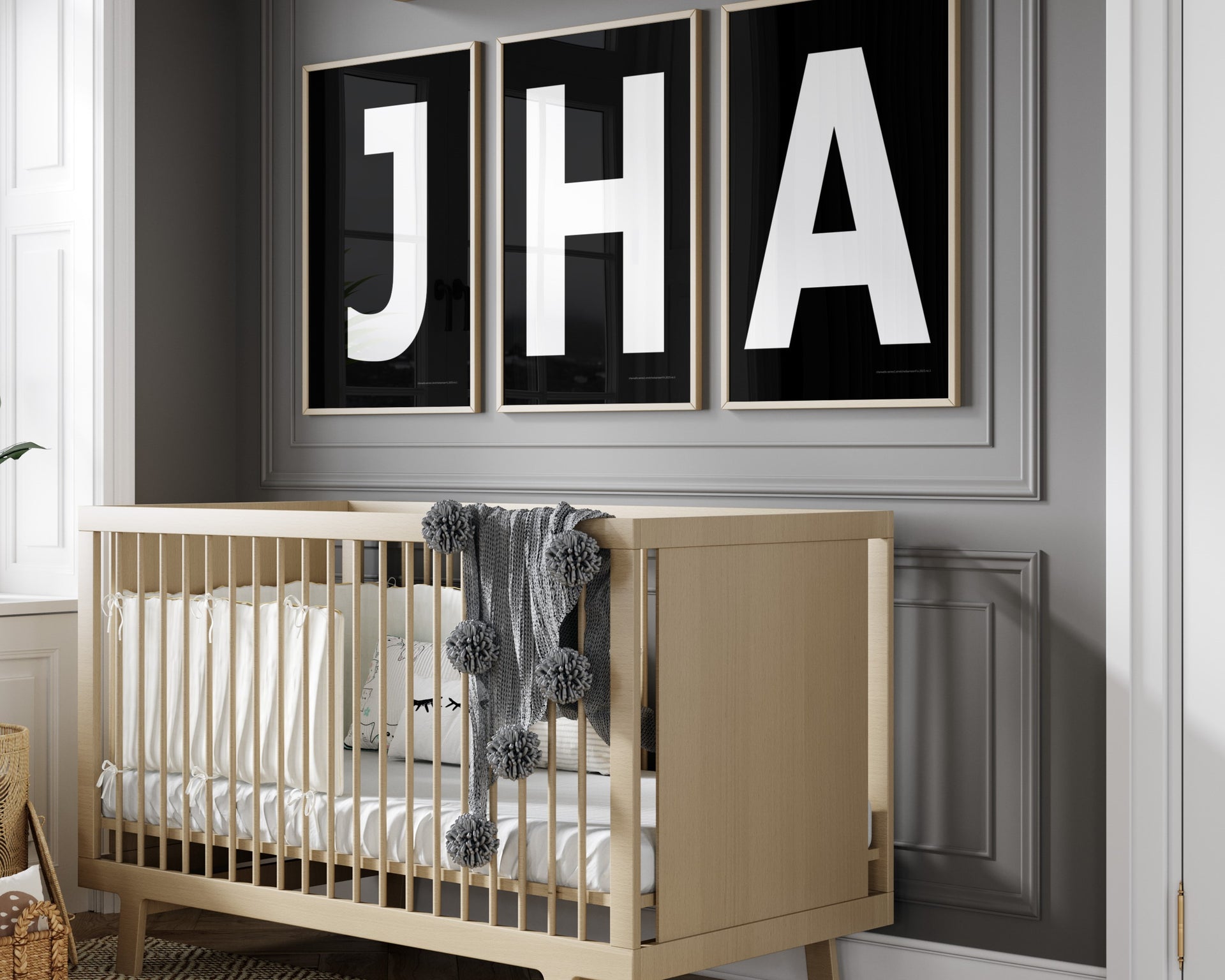 3 Framed letter art prints featuring black and white initials hanging above a crib in a gray boy nursery.