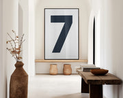 Oversized white and navy blue number 7 art print hanging in a large entryway or hallway.