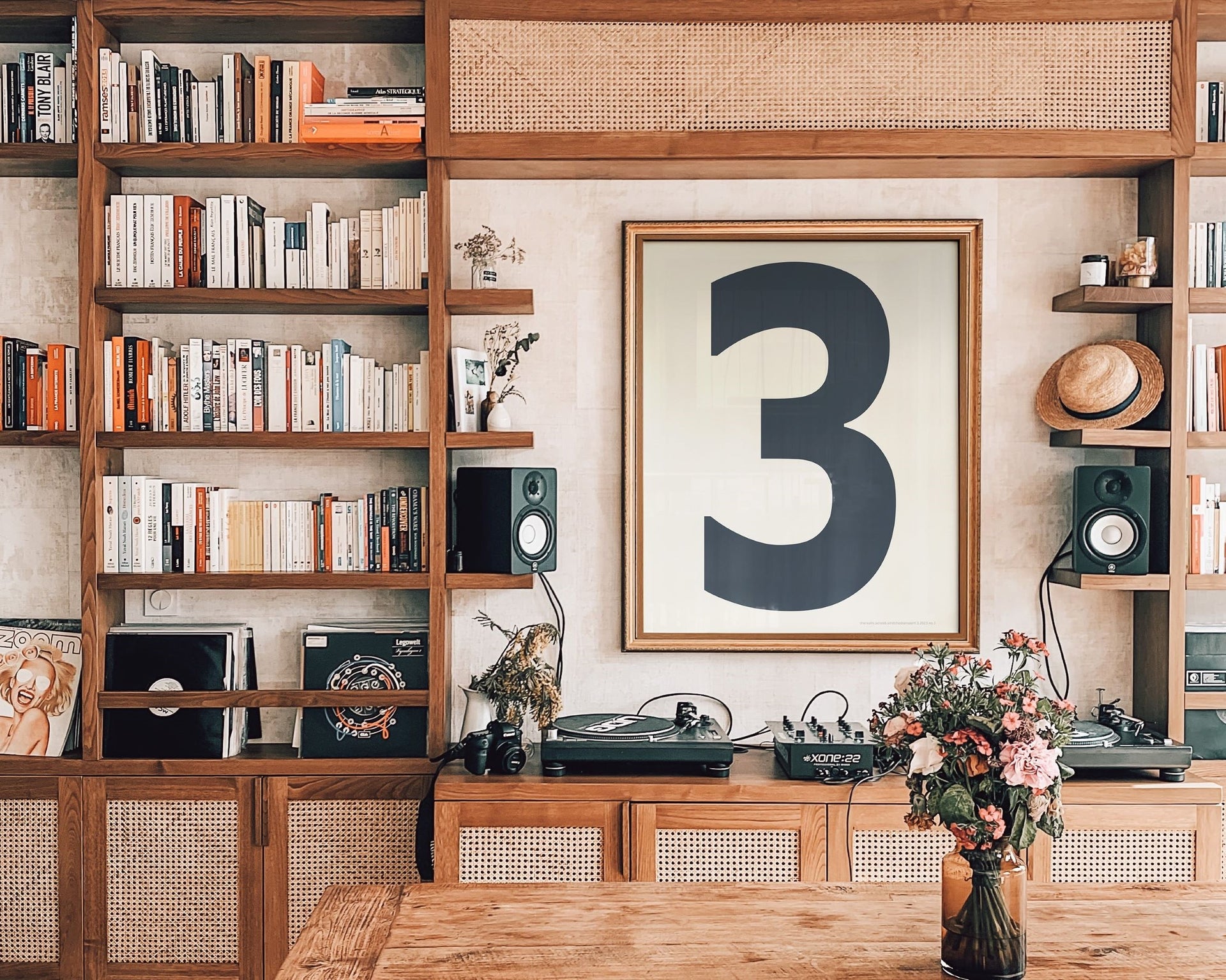 Modern library featuring a framed number art print above a mid century credenza surrounded by book shelves.