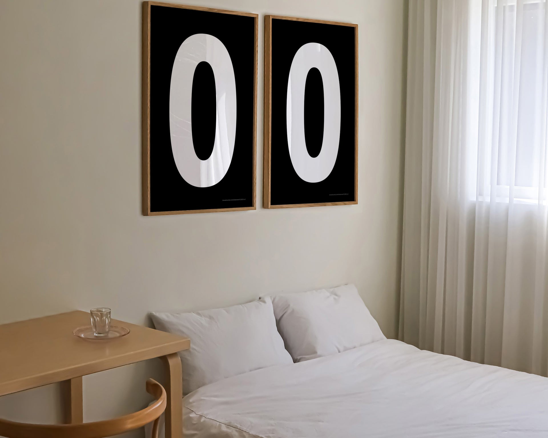 Two framed black and white number zero art prints hanging above a bed in a modern bedroom.
