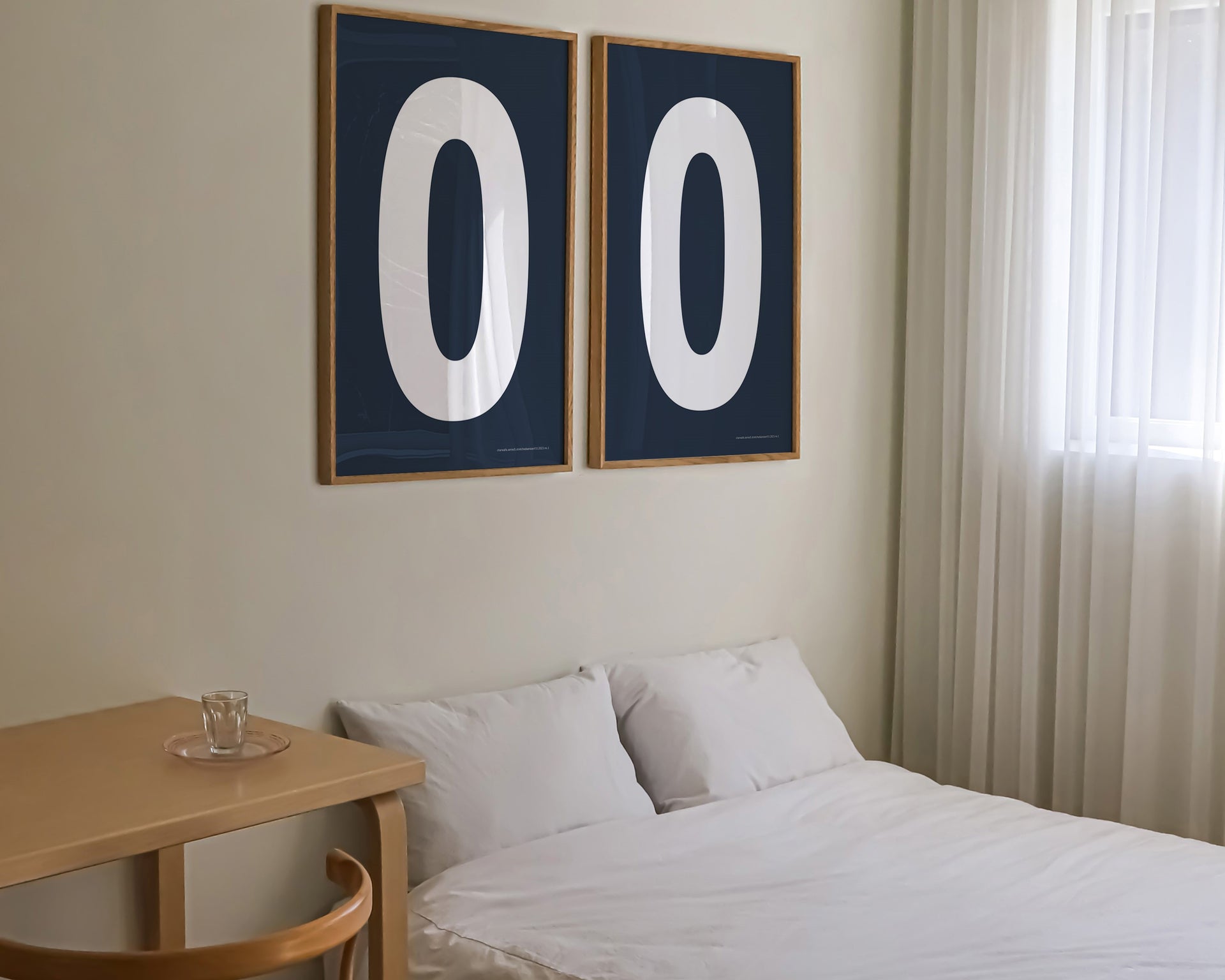 Two framed navy blue and white number zero art prints hanging above a bed in a modern bedroom.