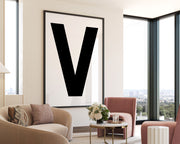 Oversized framed black and white letter V art print hanging in a modern living room.