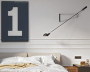 Framed navy blue and white number 1 art print hanging on a wall above a bed in a modern bedroom.