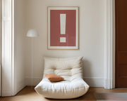 Large framed Nantucket red and white exclamation point art print hanging above a modern chair in a living room.