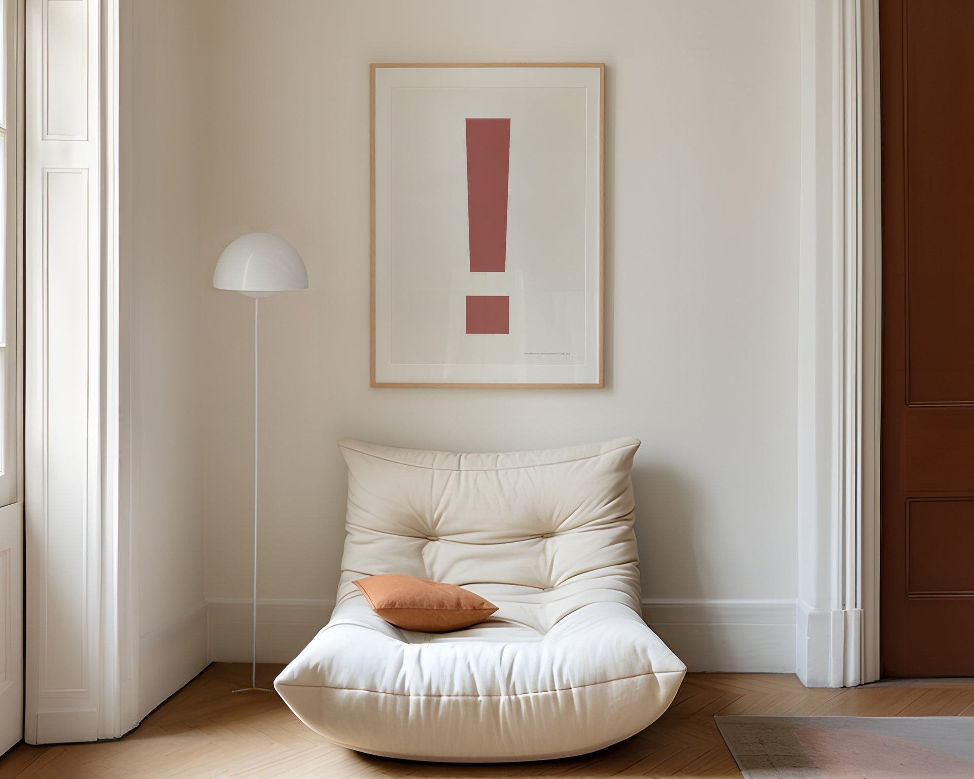Large framed Nantucket red and white exclamation point art print hanging above a modern chair in a living room.