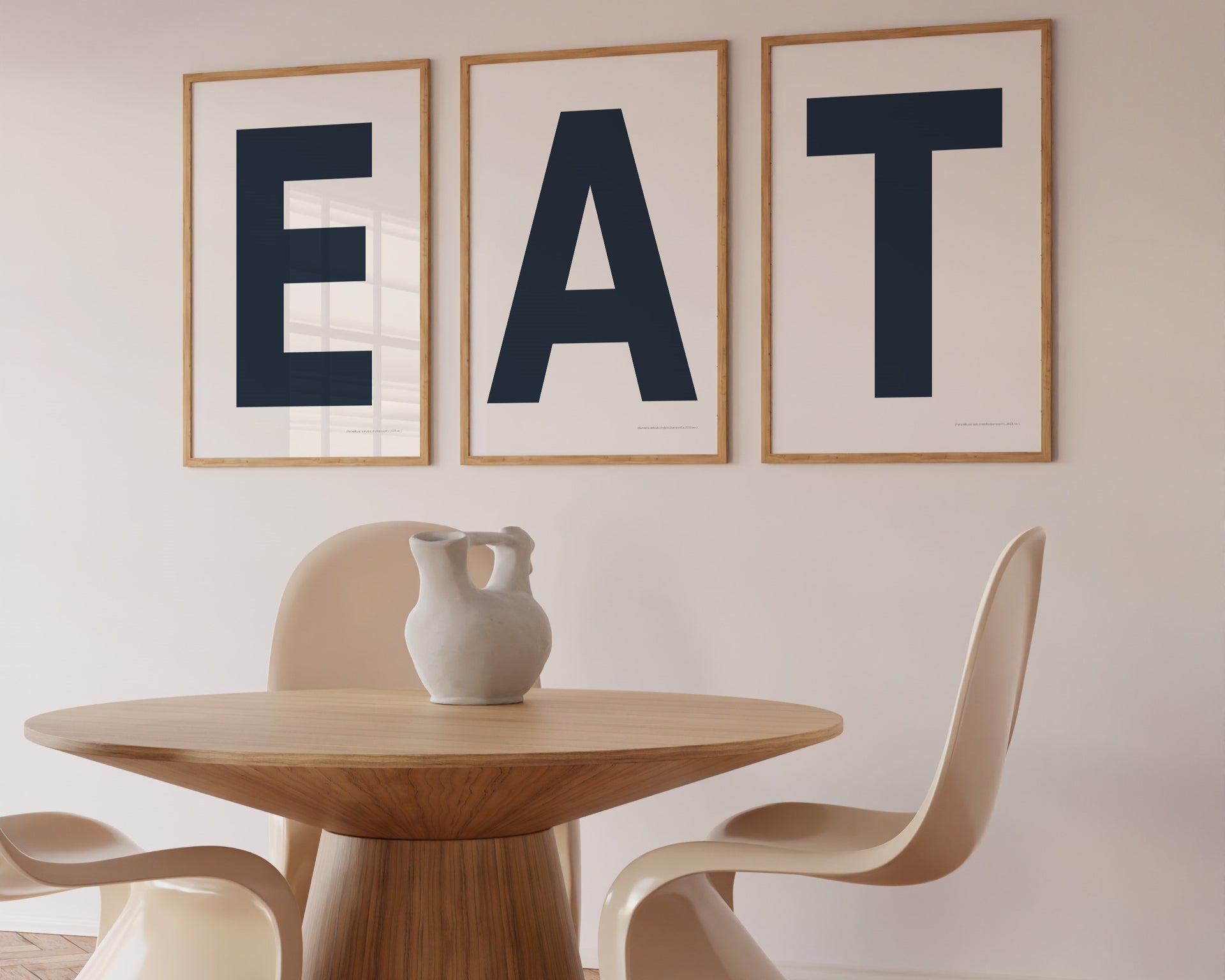 Three framed navy blue and white letter art prints spelling out the word EAT hanging in a modern dining room.