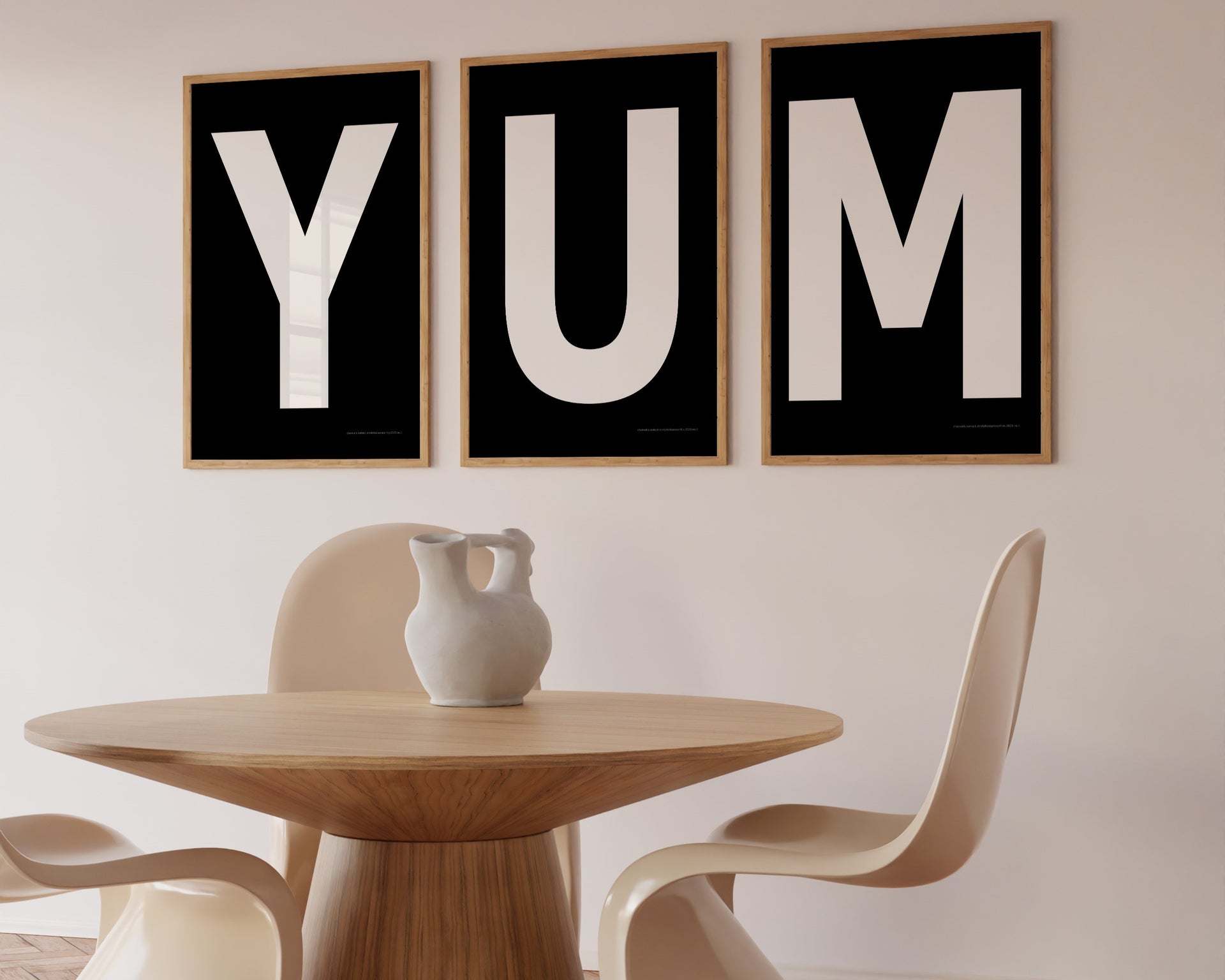 Three framed black and white letter art prints spelling out the word YUM hanging in a modern dining room.