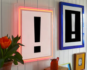 Two black and white exclamation points framed in neon pink and blue frames.