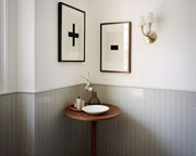Two framed plus and minus art prints in a bathroom with green tile.