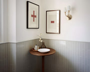 Two framed plus and minus art prints in a bathroom with green tile.