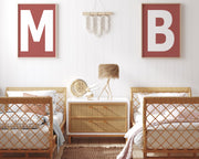 Two framed Nantucket red and white letter art prints showing initials above twin beds.