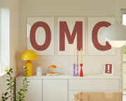 Three framed Nantucket red and white letter art prints spelling out OMG hanging above a credenza.