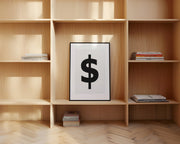 Framed black and white dollar sign art print leaning on a shelf.