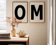 Two framed black and white letter art prints spelling out OM in a dining room.