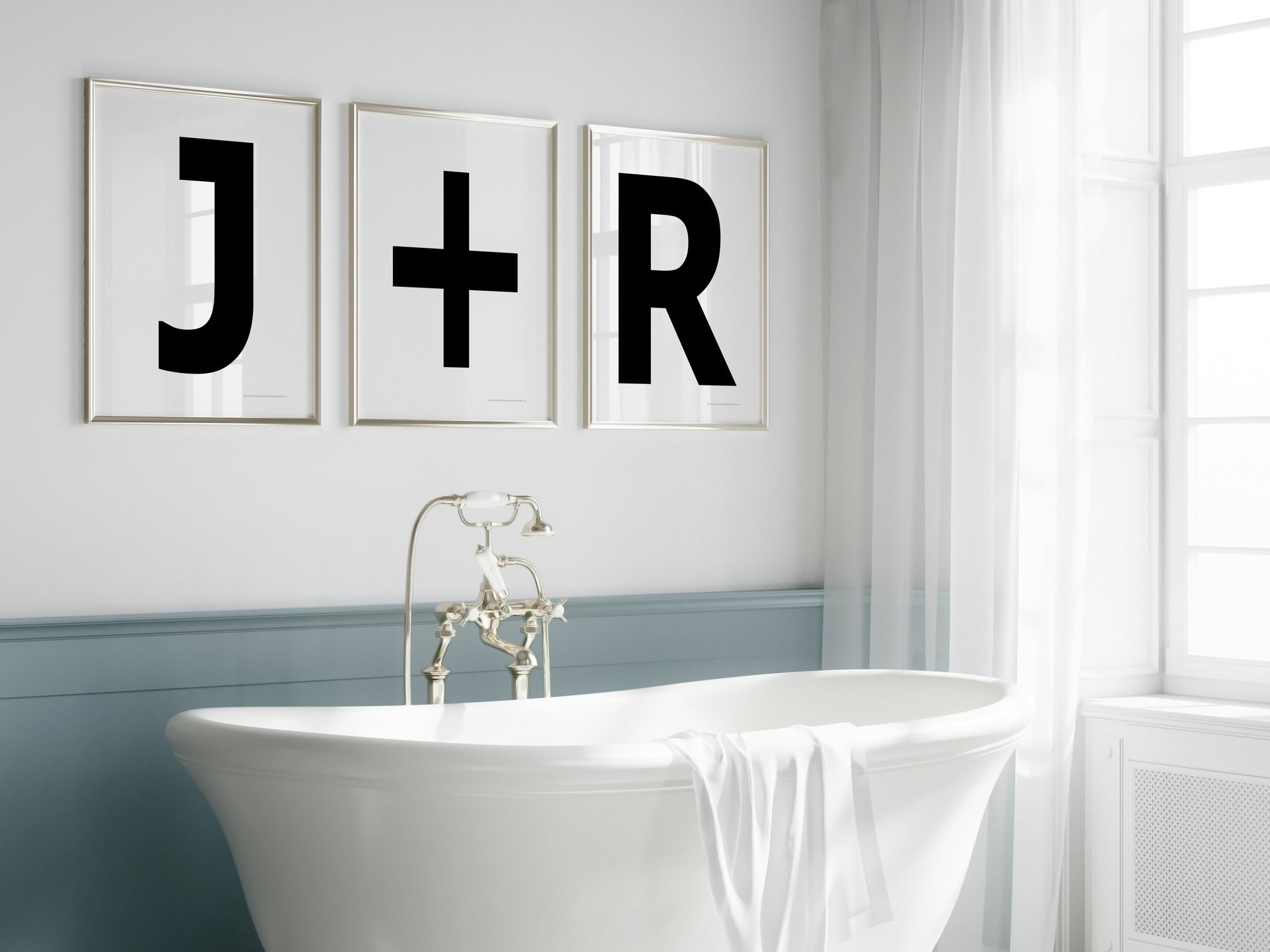 Three framed black and white letter and plus sign art prints spelling out a couple's initials J+R hanging above a bathtub.