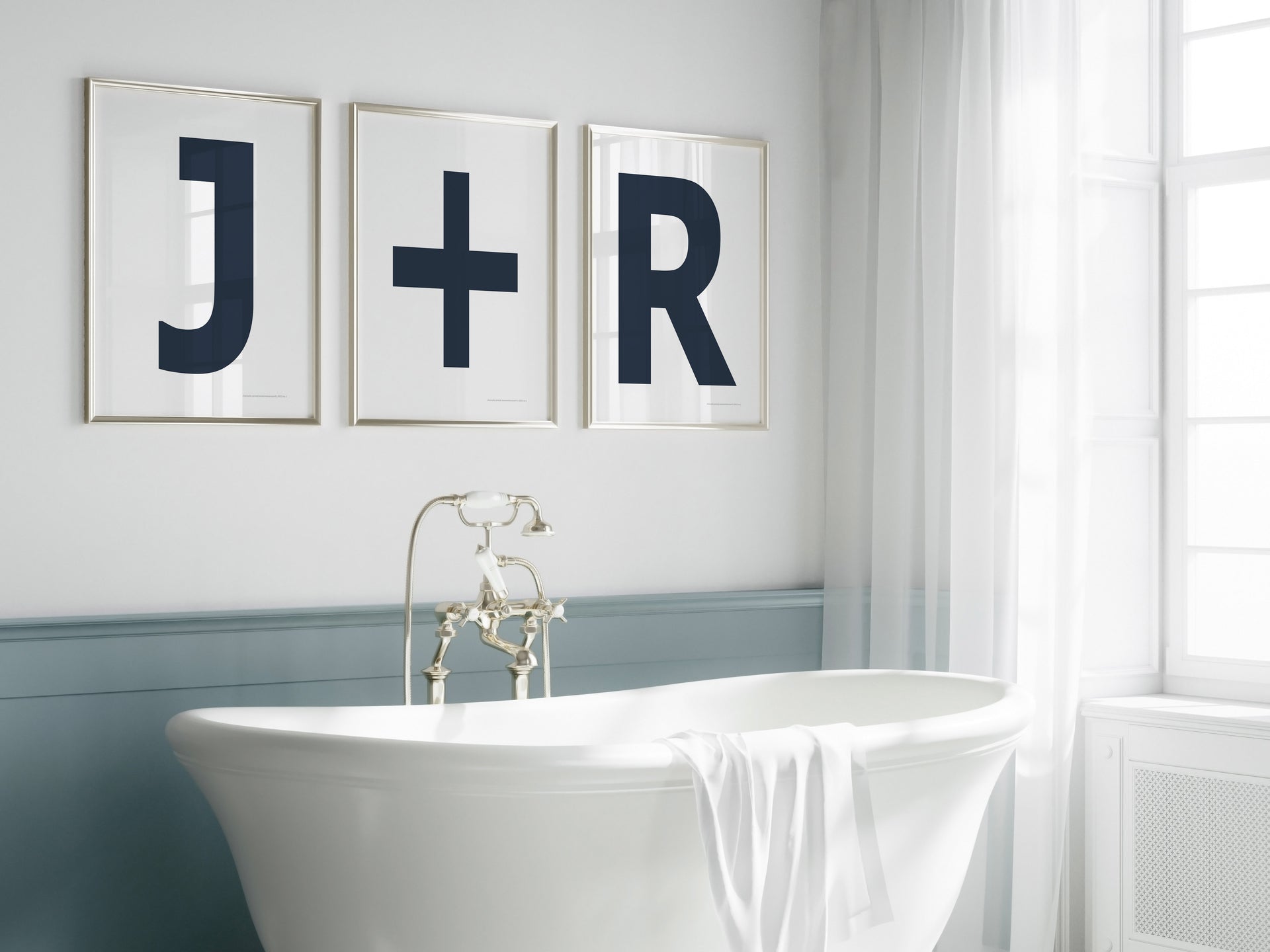 Three framed navy blue and white letter and plus sign art prints spelling out a couple's initials J+R hanging above a bathtub.