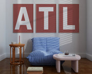 Three large framed Nantucked red and white letter art prints spelling out ATL hanging above a blue chair.