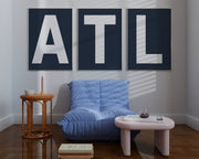 Two framed navy blue and white letter art prints spelling out LA hanging in a bright white dining room.
