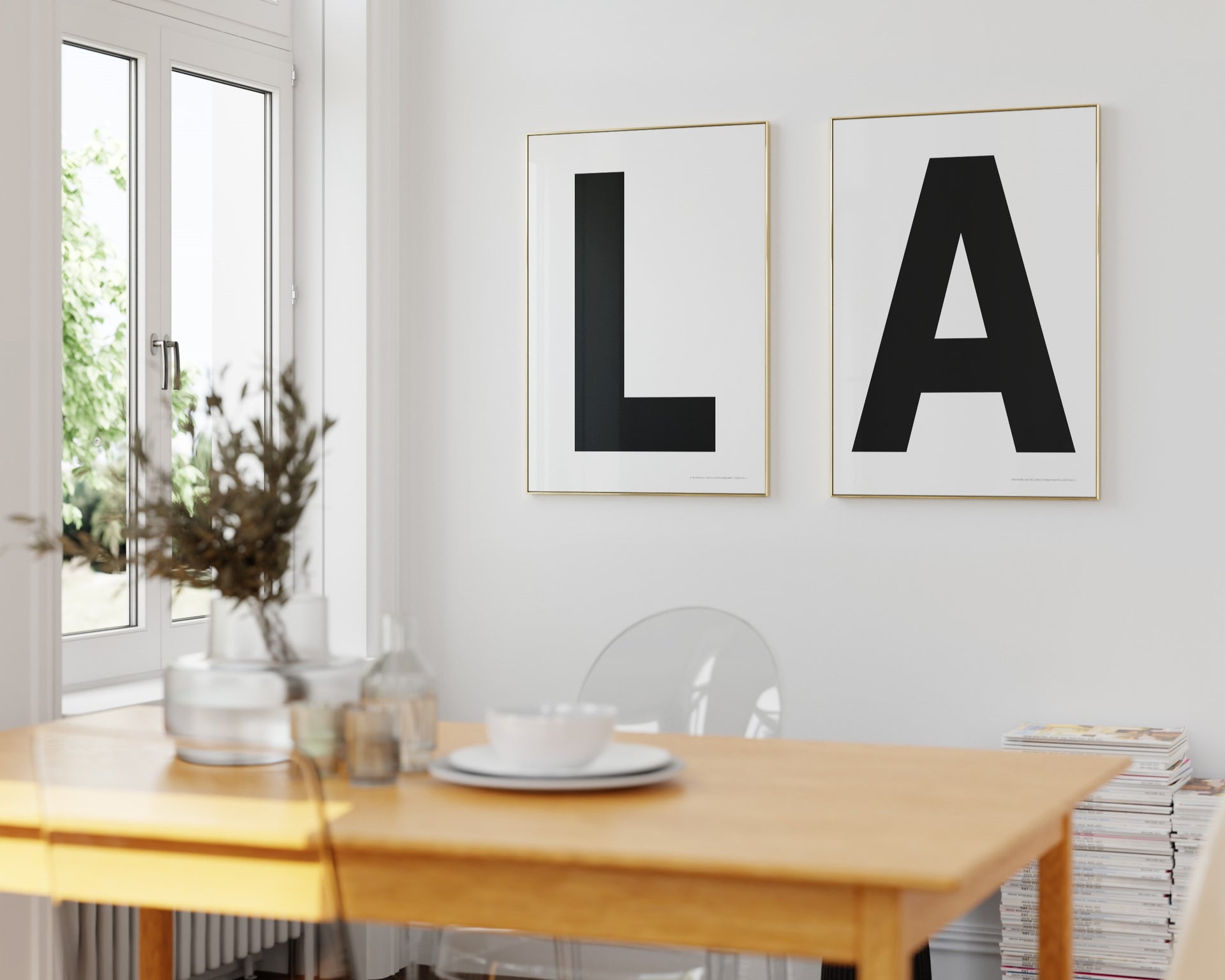 Two framed black and white letter art prints spelling out LA hanging in a bright white dining room.