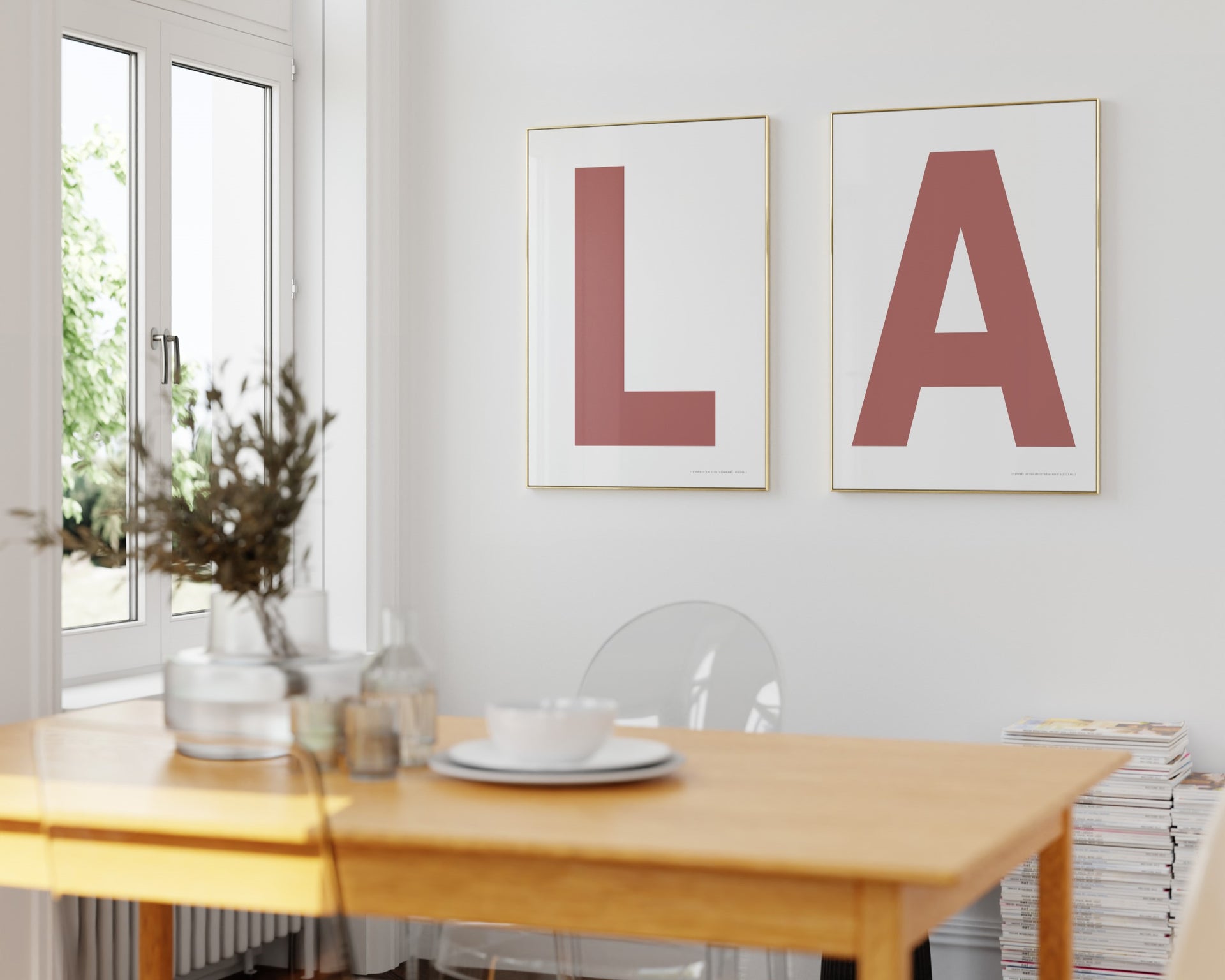 Two framed white and Nantucket red letter art prints spelling out LA hanging in a bright white dining room.