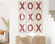 Nine framed white and Nantucket red letter art prints featuring X and O creating tic tac toe on the wall.