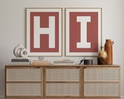 Two framed Nantucket red and white letter art prints spelling out HI hanging above a credenza in a hallway or entryway.