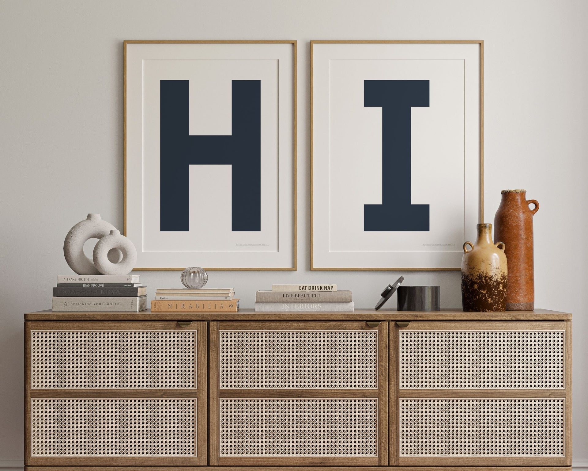 Two framed navy blue and white letter art prints spelling out HI hanging above a credenza in a hallway or entryway.