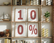 Four framed number and percent sign art prints spelling out 100% on a boho bookshelf.