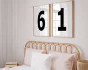 Two framed black and white number frames featuring a girl's jersey numbers hanging above the bed.