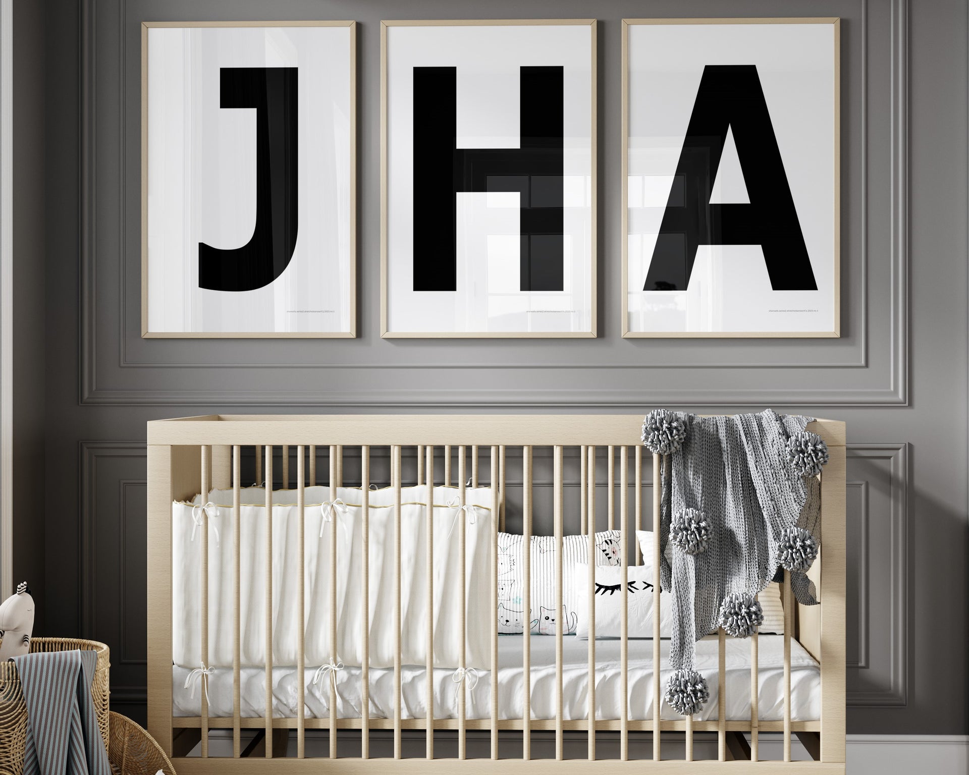 3 Framed letter art prints featuring black and white initials hanging above a crib in a gray boy nursery hanging on the wall.