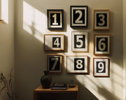 Nine small black and white framed number art prints 1 through 9 in a hallway or entryway.