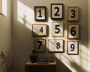 Nine small black and white framed number art prints 1 through 9 in a hallway or entryway.