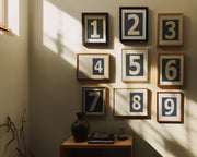 Nine small navy blue and white framed number art prints 1 through 9 in a hallway or entryway.