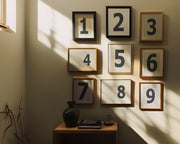 Nine small navy blue and white framed number art prints 1 through 9 in a hallway or entryway.