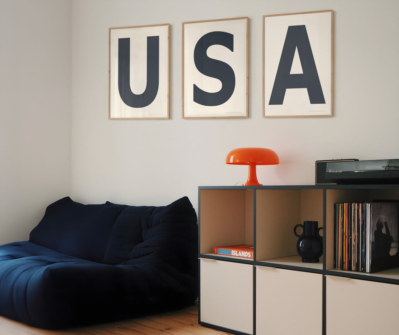 Three framed white and navy blue letter art prints spelling out USA on a white wall in a boy or teen bedroom or playroom.