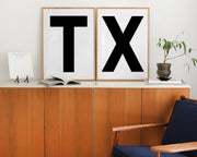 Two framed letter art prints spelling TX on a credenza