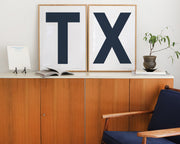 Two framed letter art prints spelling TX on a credenza