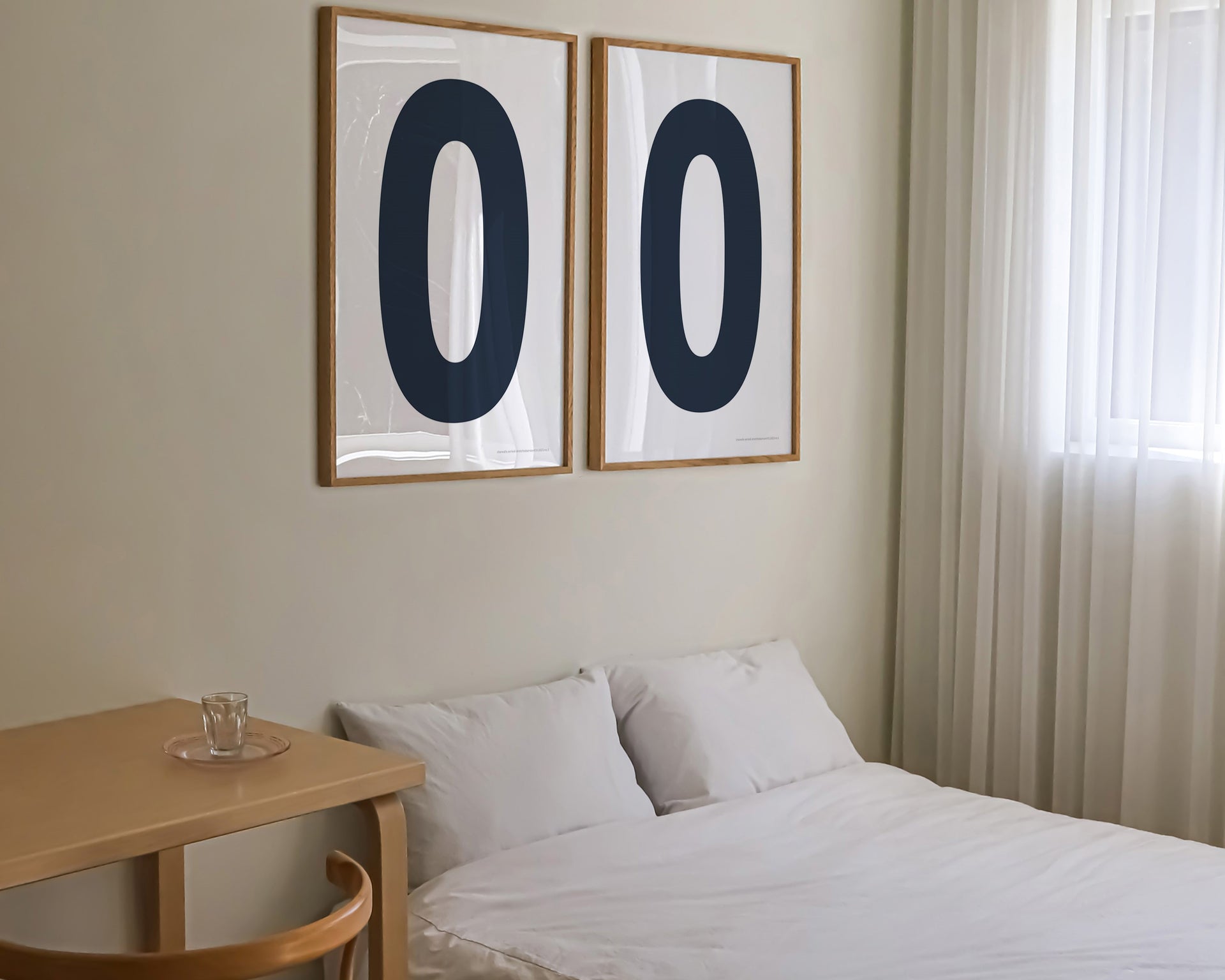 Two framed navy blue and white number zero art prints hanging above a bed in a modern bedroom.