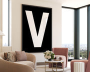 Oversized framed black and white letter V art print hanging in a modern living room.