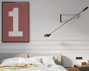 Framed Nantucket red and white number 1 art print hanging on a wall above a bed in a modern bedroom.