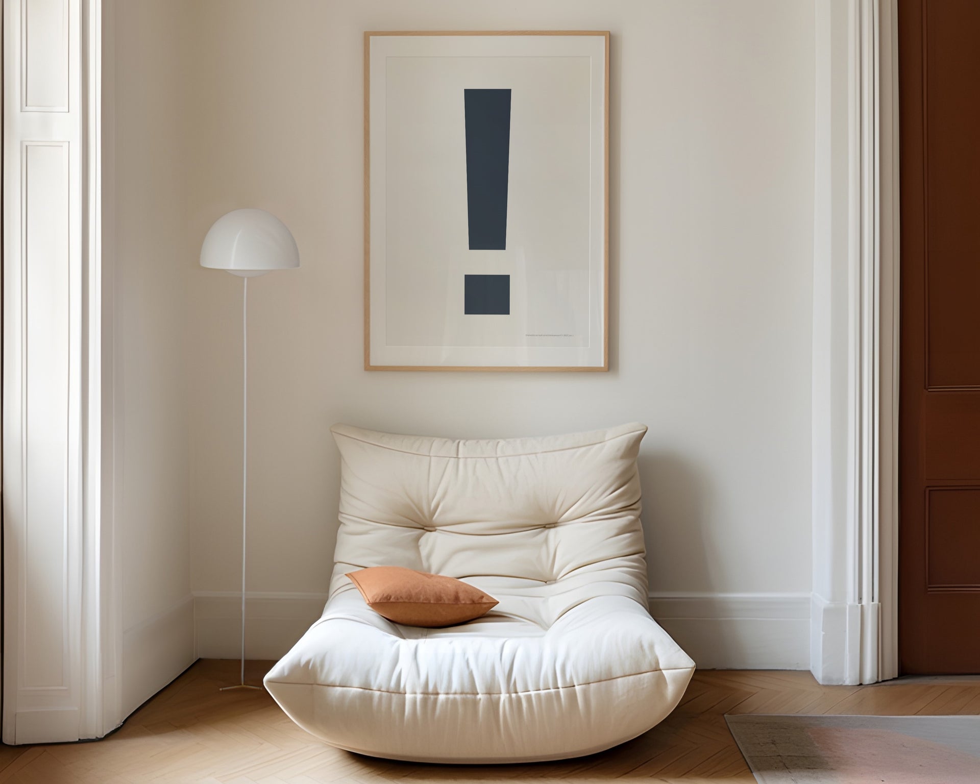 Large framed navy blue and white exclamation point art print hanging above a modern chair in a living room.