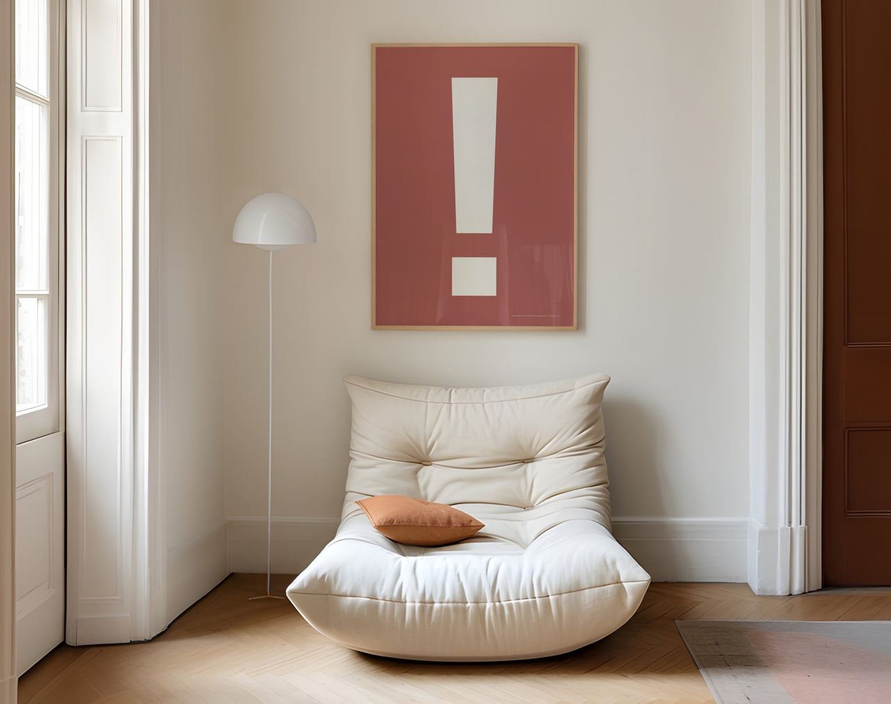 Large framed Nantucket red and white exclamation point art print hanging above a modern white chair.