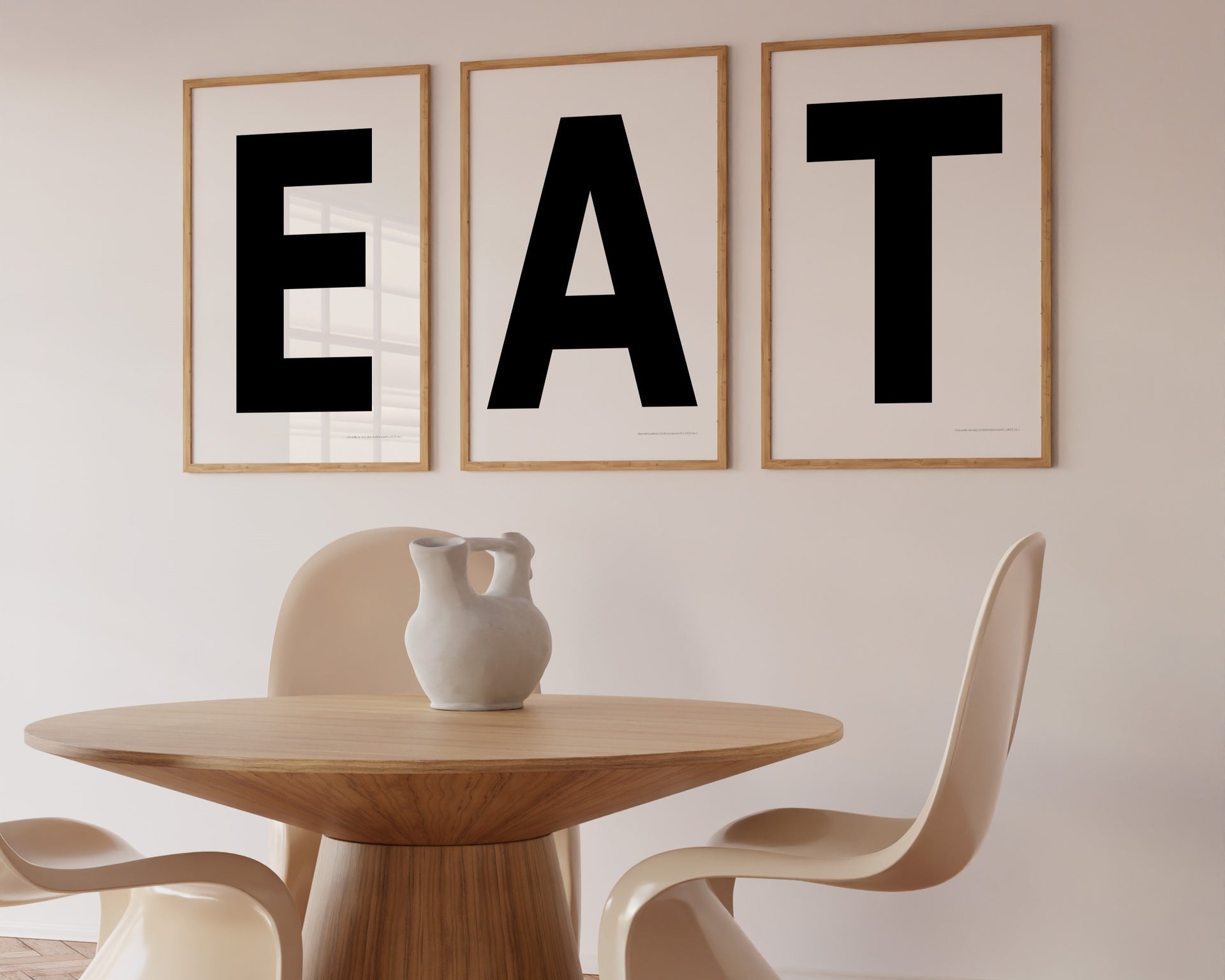 Three framed white and black letter art prints spelling out the word EAT hanging in a modern dining room.